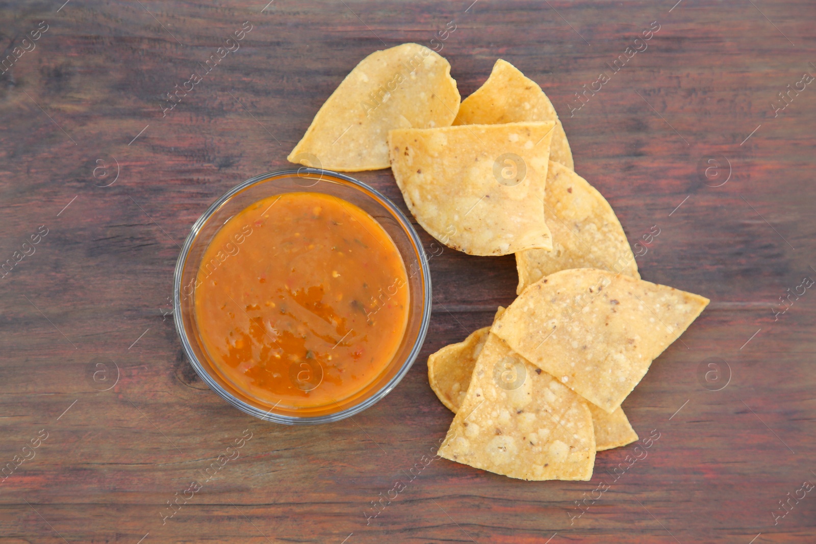 Photo of Tasty salsa sauce and Mexican nacho chips on wooden table, flat lay