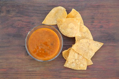 Tasty salsa sauce and Mexican nacho chips on wooden table, flat lay