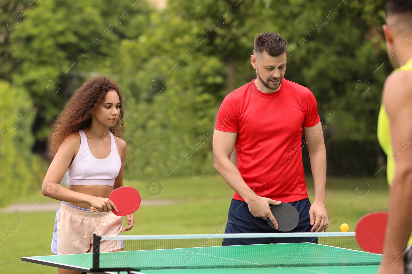 Photo of Friends playing ping pong outdoors on summer day