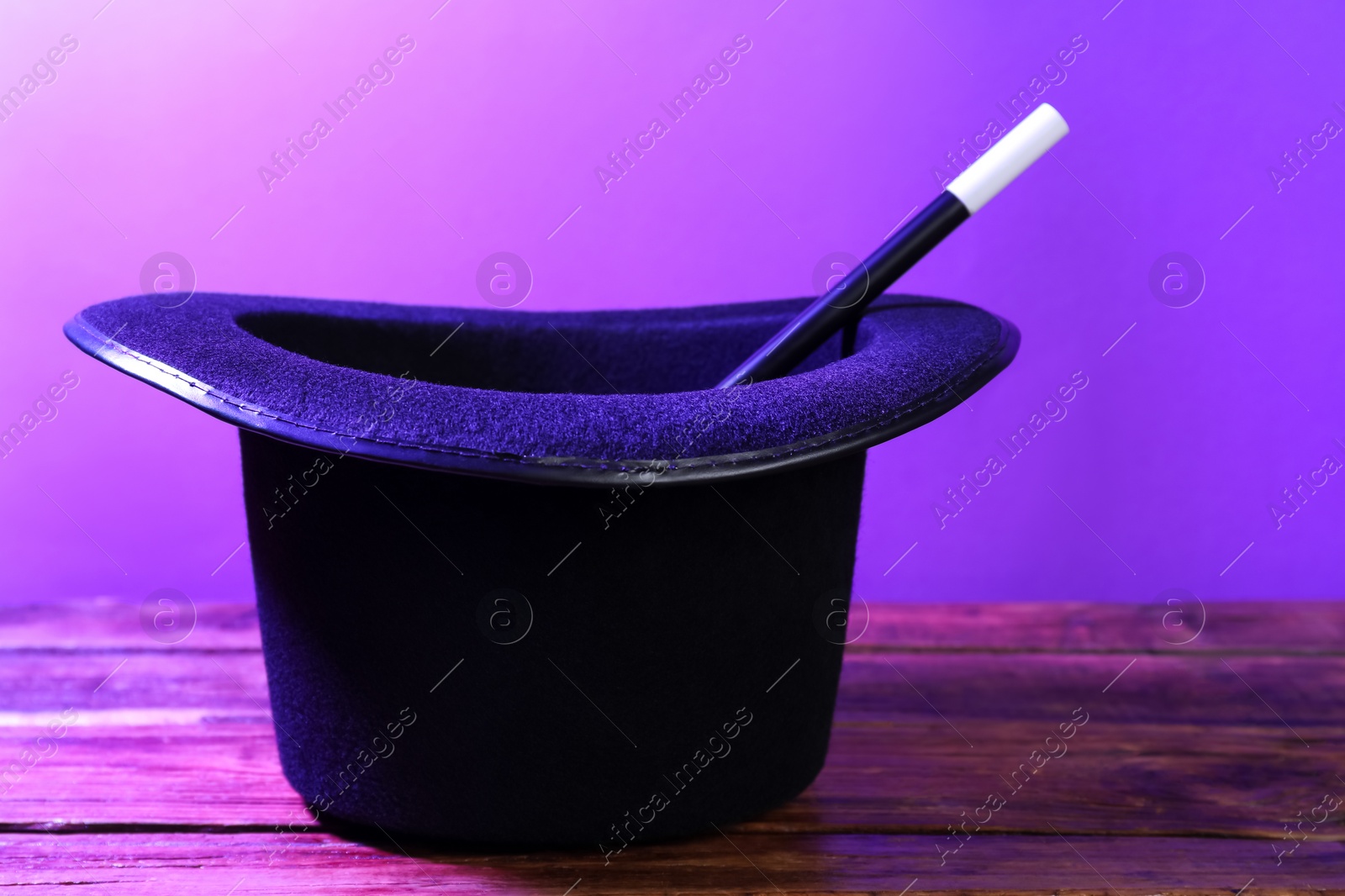 Photo of Black top hat and wand on wooden table. Magician equipment