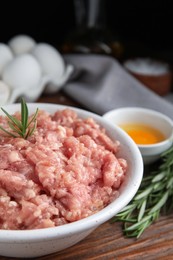 Photo of Raw chicken minced meat with rosemary on wooden table, closeup