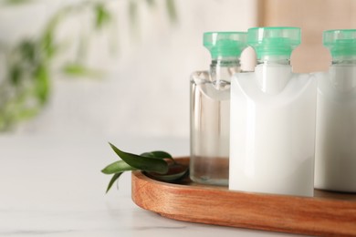 Photo of Mini bottles of cosmetic products on white table against blurred background, closeup. Space for text