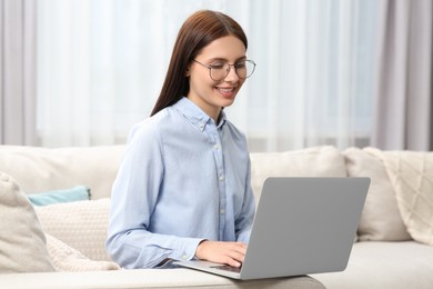 Smiling woman in stylish eyeglasses working with laptop at home