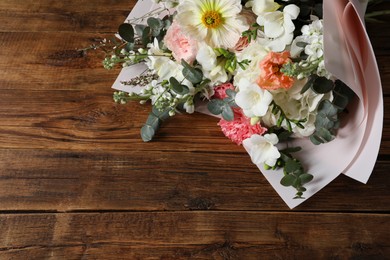 Photo of Bouquet of beautiful flowers on wooden table, above view. Space for text