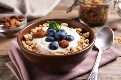 Photo of Bowl of tasty oatmeal with blueberries and yogurt on wooden table
