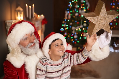 Photo of Little child with Santa Claus and Christmas star at home