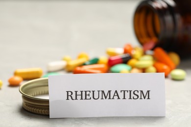 Photo of Card with word Rheumatism and pills on light table