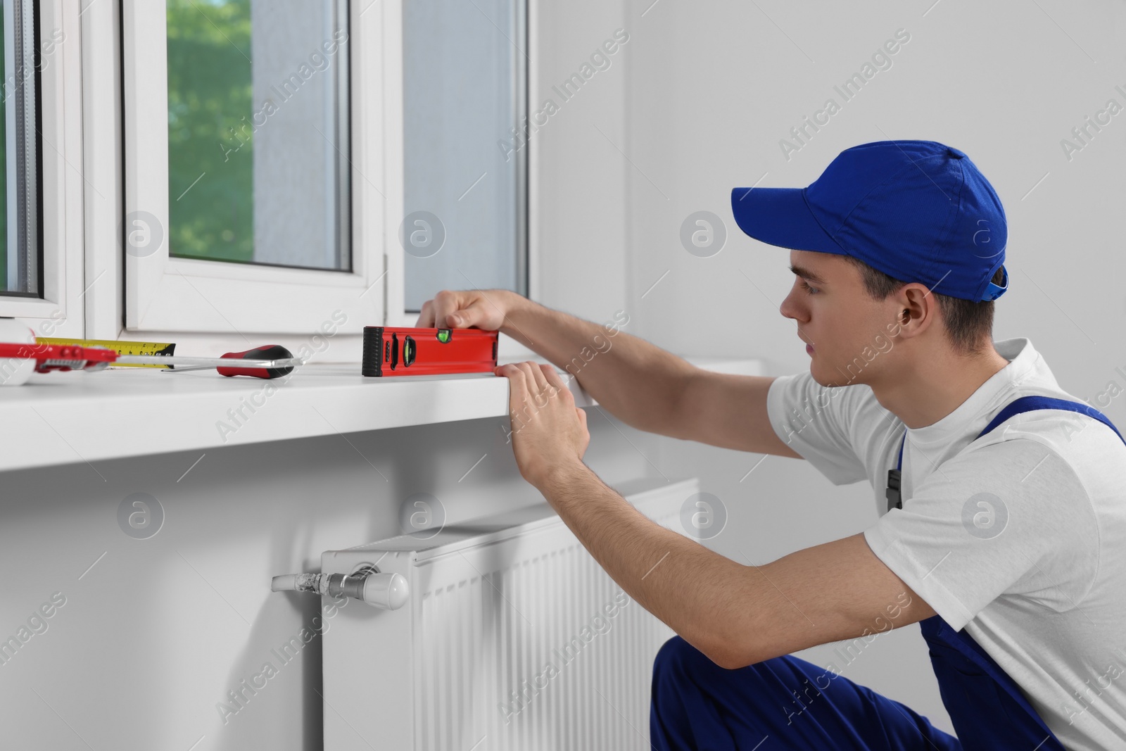 Photo of Worker using bubble level after plastic window installation indoors