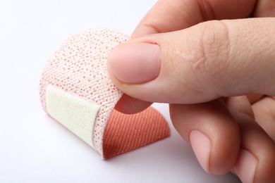 Photo of Woman putting sticking plaster on white background, closeup. First aid item