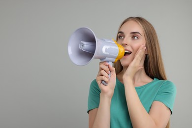 Photo of Special promotion. Young woman shouting in megaphone on grey background, space for text
