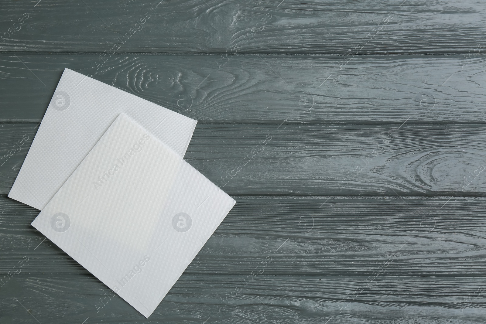 Photo of Clean napkins on grey wooden table, flat lay. Space for text