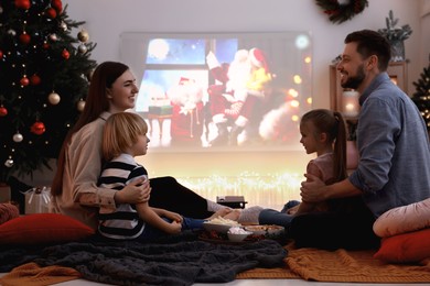 Happy family spending time together near video projector in cosy room. Christmas atmosphere