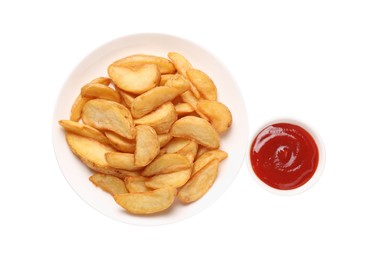 Delicious baked potato wedges and ketchup in bowl on white background, top view