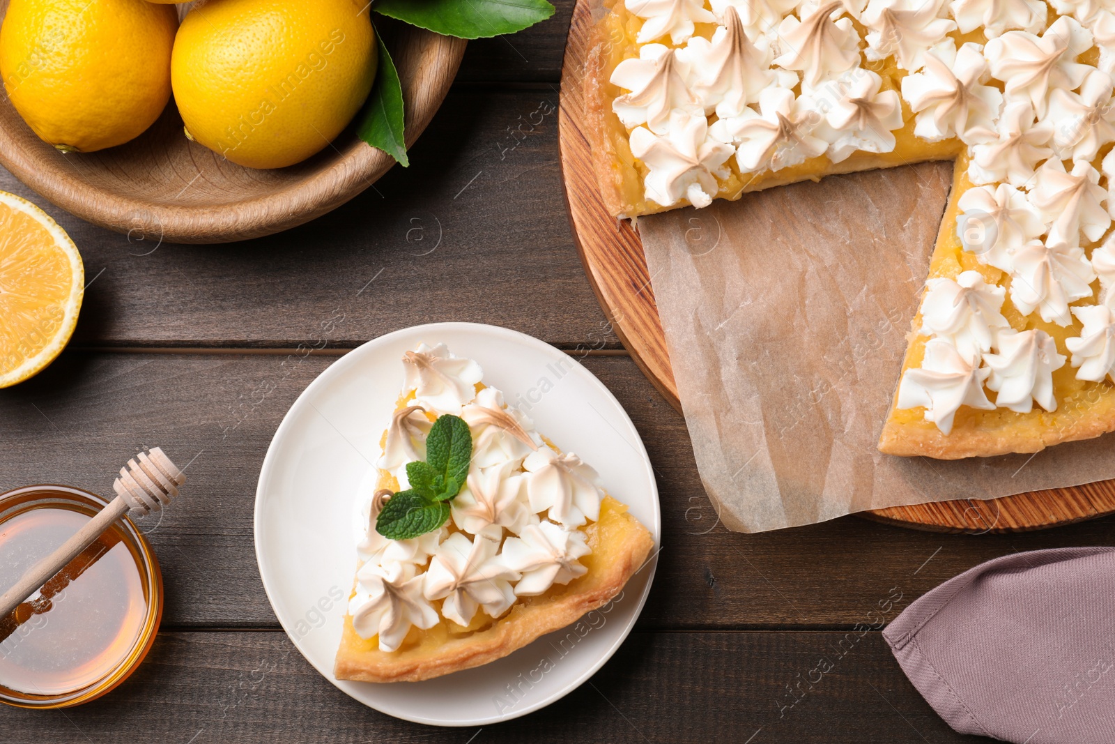 Photo of Cut delicious lemon meringue pie served on wooden table, flat lay