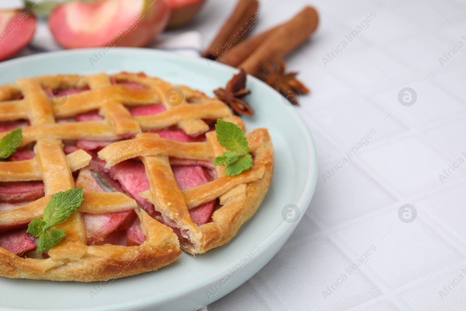 Photo of Delicious apple pie with mint on white tiled table, closeup. Space for text