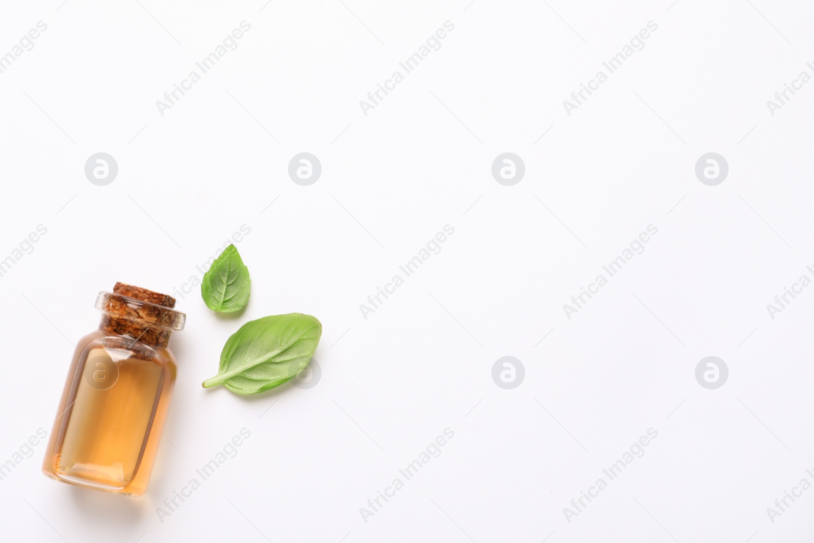 Photo of Bottle of essential basil oil and fresh leaves on white background, flat lay. Space for text