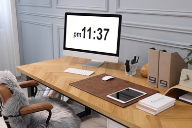 Stylish workplace with computer and stationery on wooden desk near grey wall at home