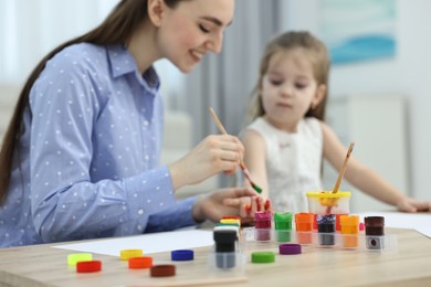 Mother and her little daughter painting with palms at home, selective focus