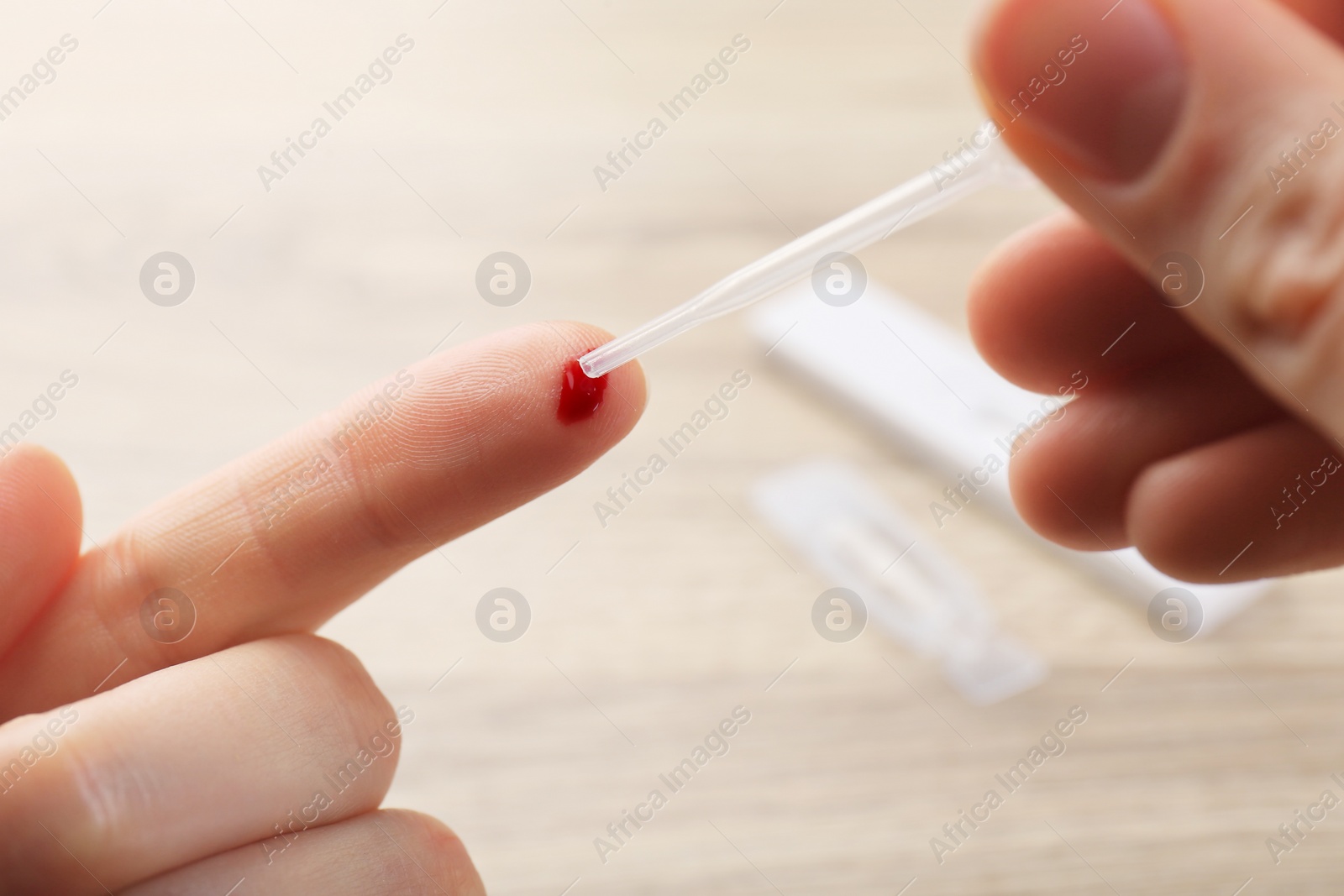 Photo of Laboratory testing. Woman taking blood sample from finger with pipette on blurred background, closeup