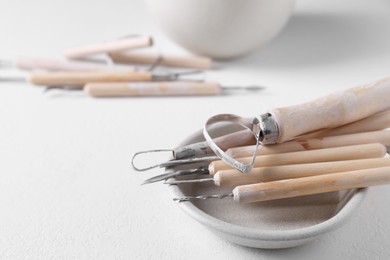 Photo of Set of different clay crafting tools on white table. Space for text