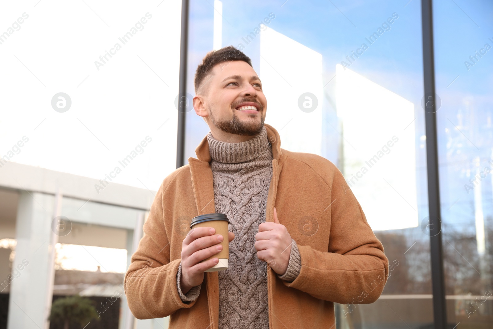 Photo of Man with cup of coffee on city street in morning