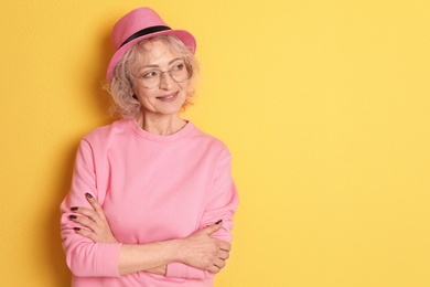 Photo of Portrait of mature woman in hipster outfit on color background. Space for text