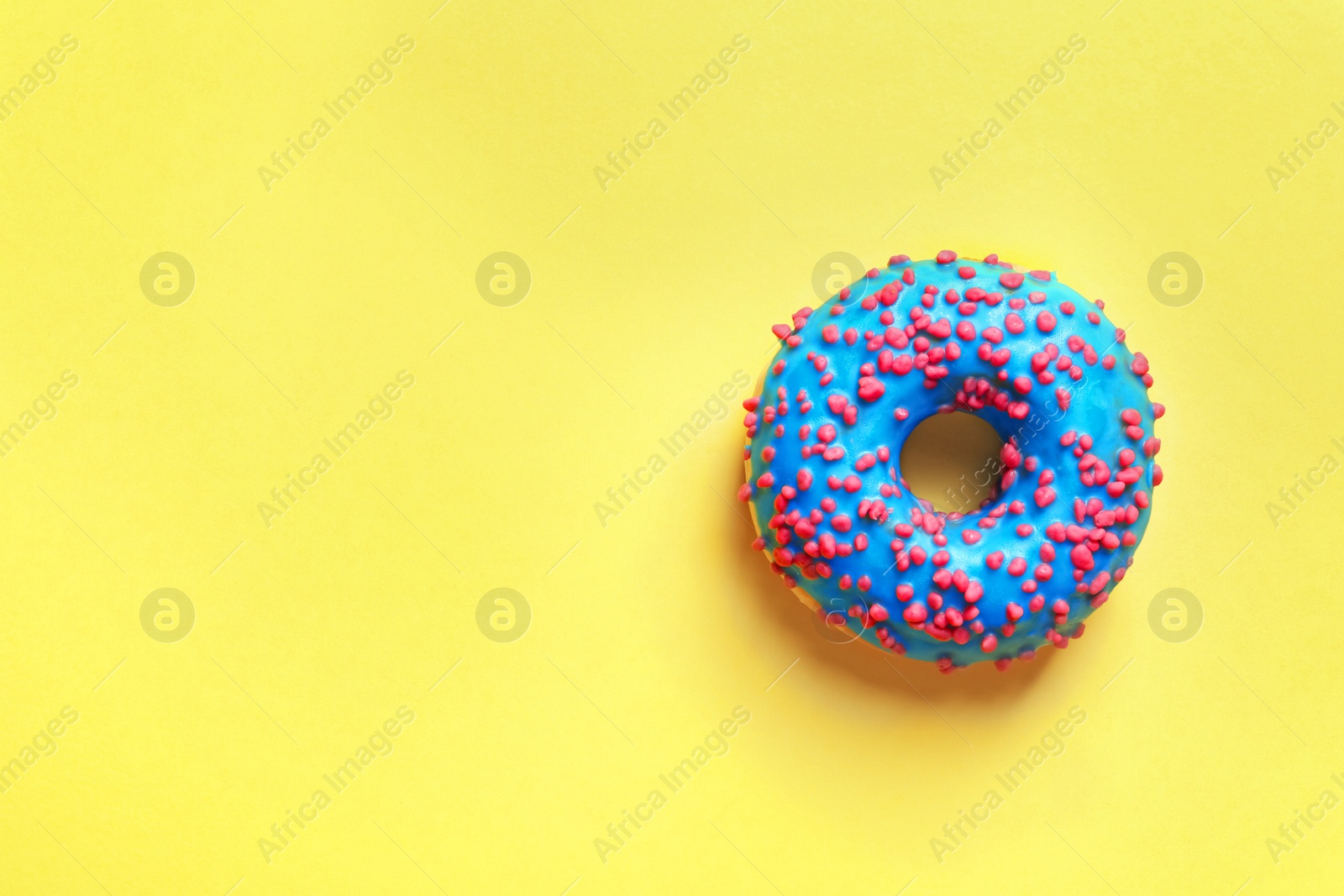 Photo of Delicious glazed doughnut with sprinkles on color background, top view