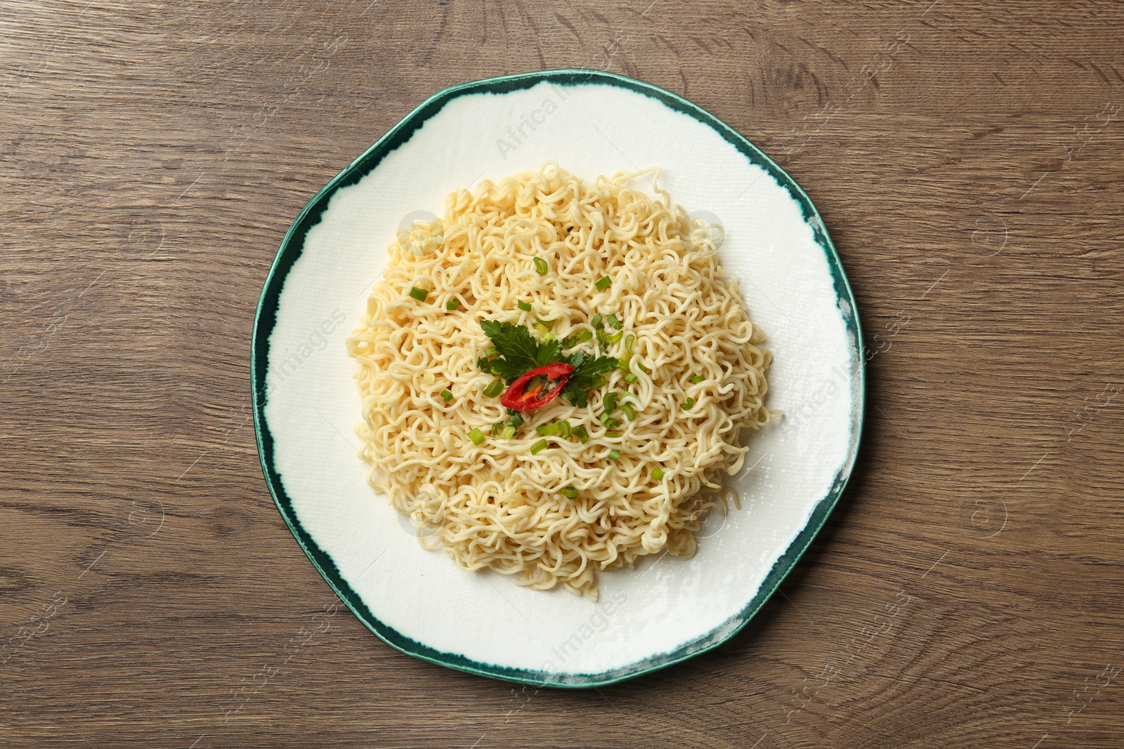 Photo of Plate of tasty noodles on wooden background, top view