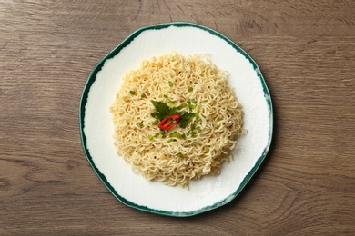 Plate of tasty noodles on wooden background, top view