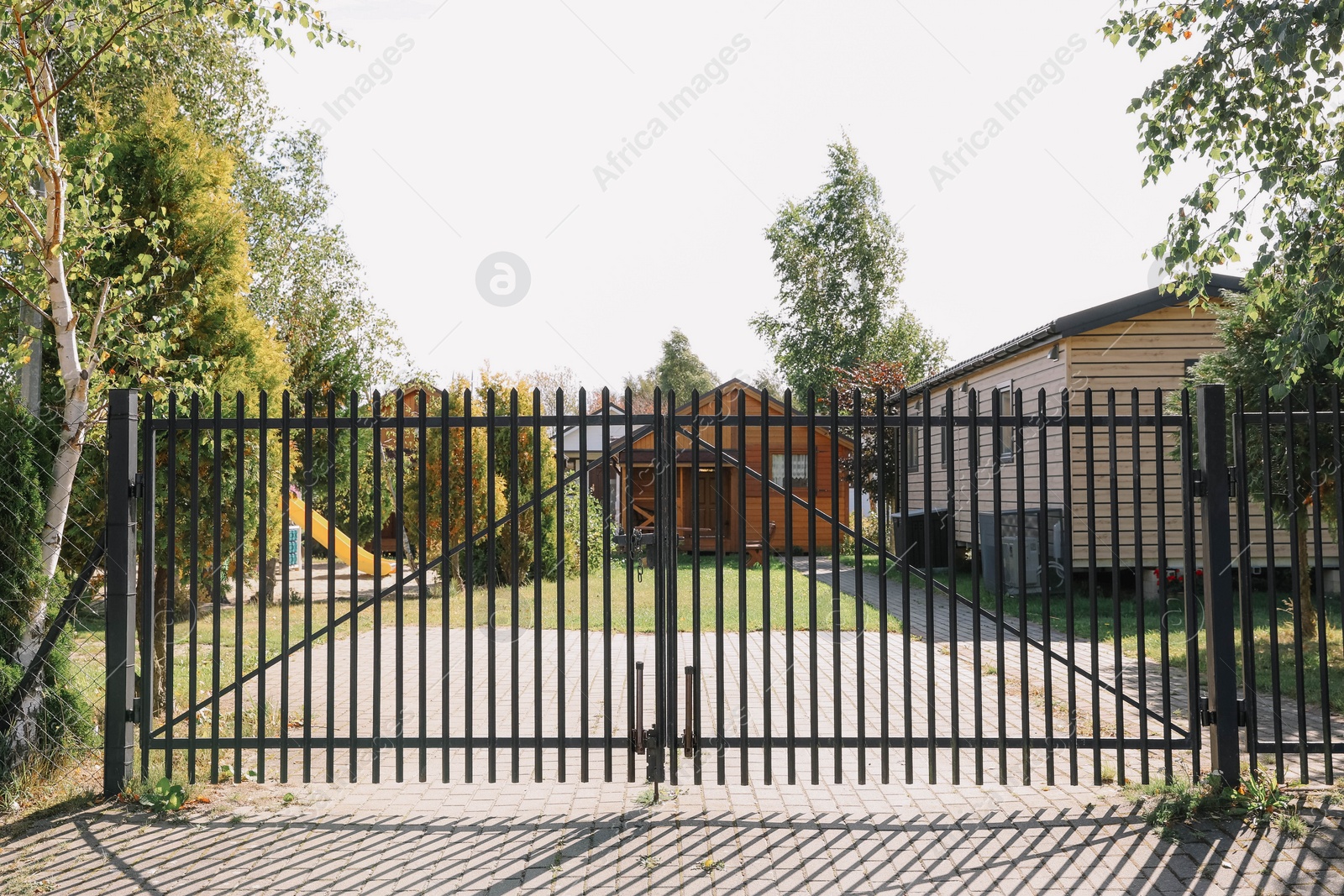 Photo of Metal gates near houses and trees on sunny day