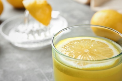 Photo of Glass with fresh lemon juice on table, closeup