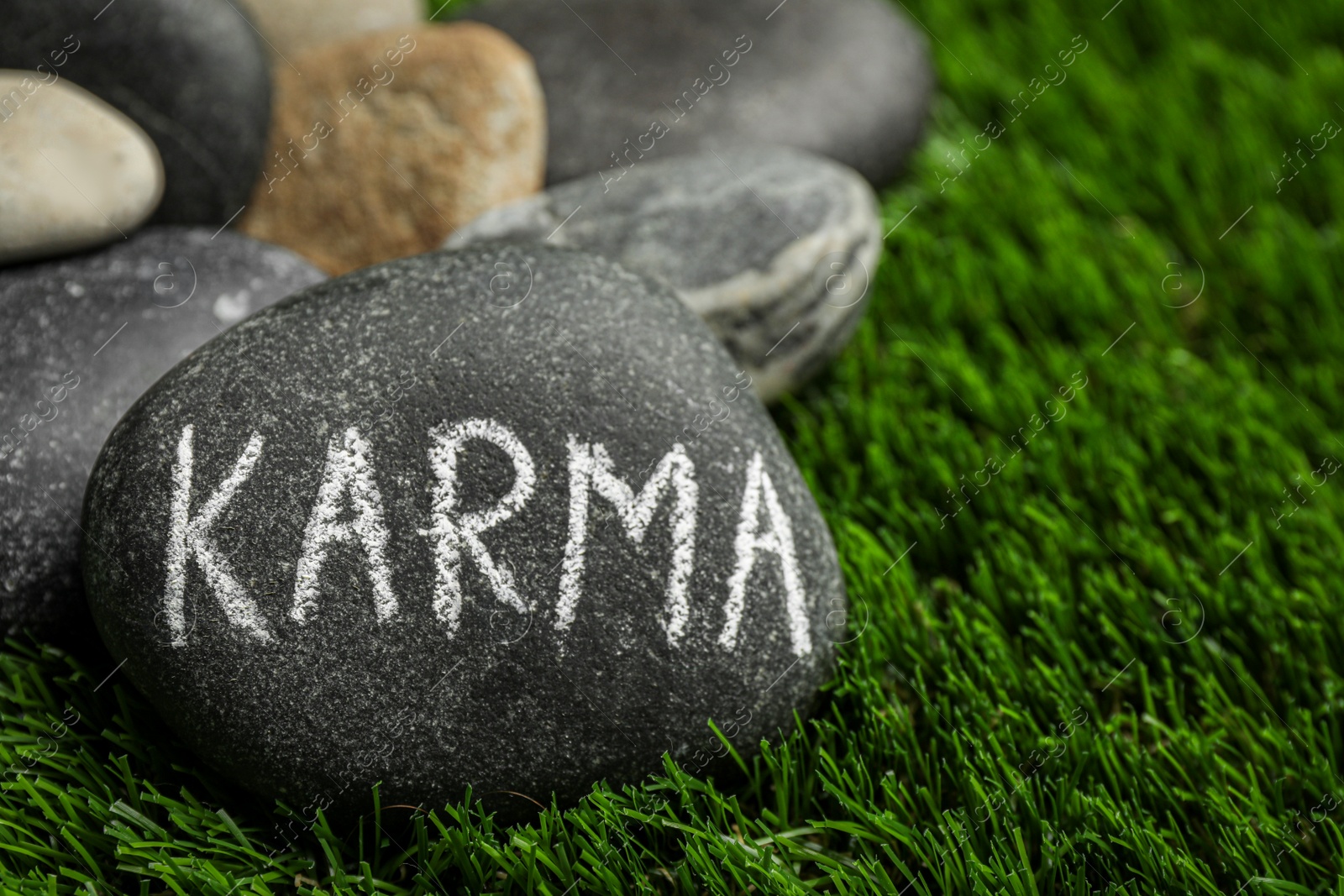 Photo of Stones with word Karma on green grass, closeup. Space for text