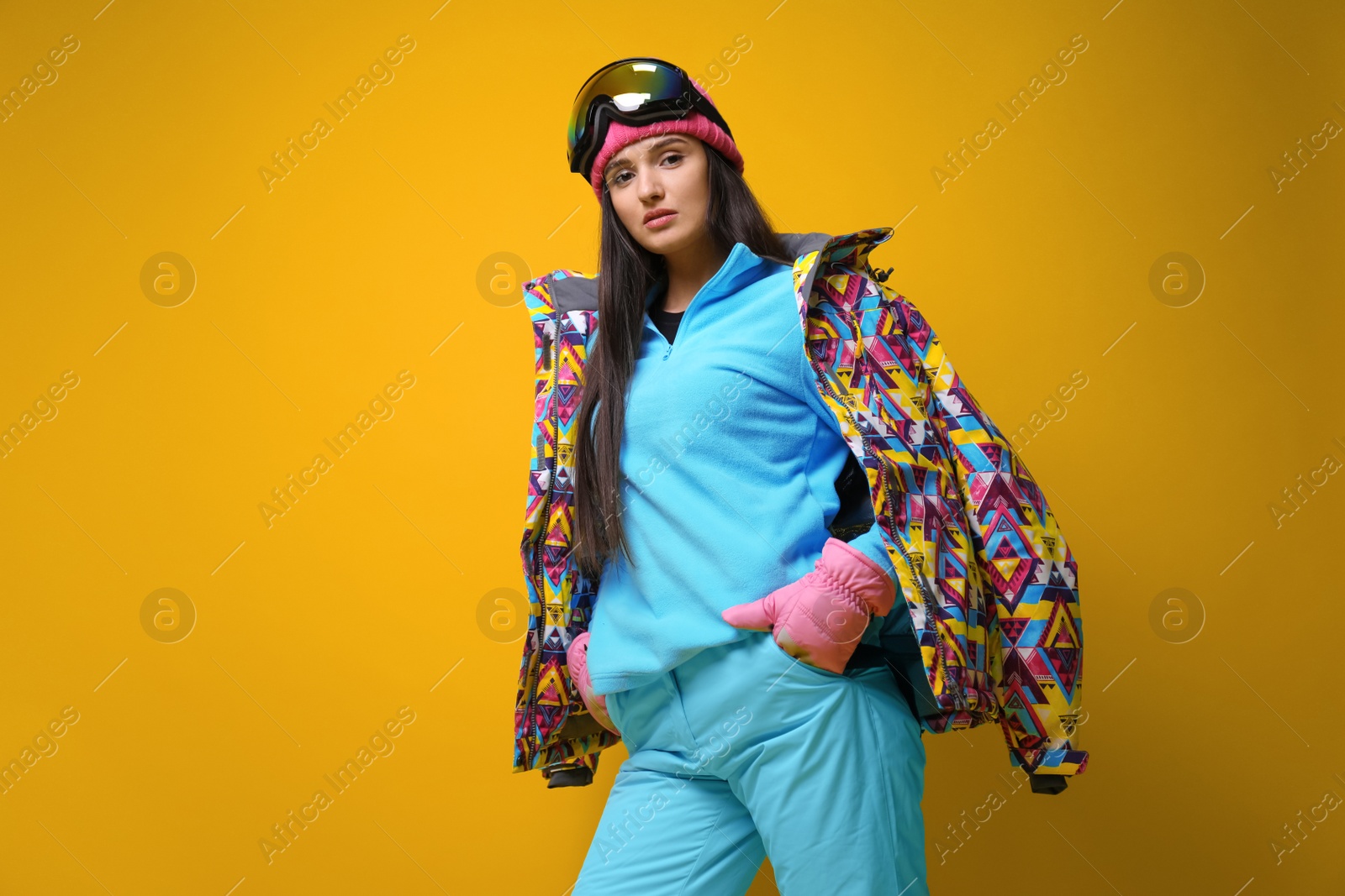 Photo of Woman wearing stylish winter sport clothes on yellow background, low angle view