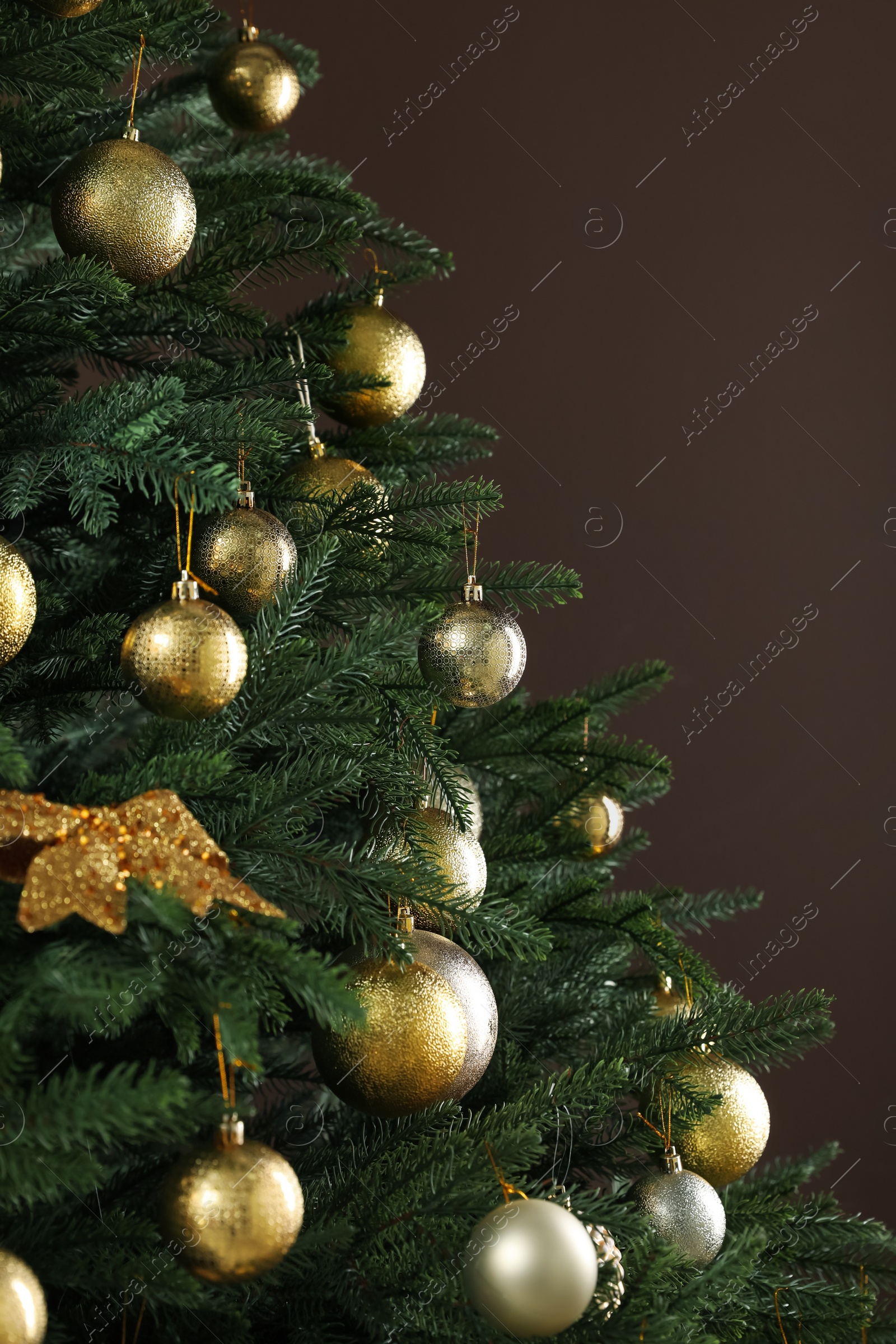 Photo of Beautifully decorated Christmas tree on brown background, closeup. Space for text