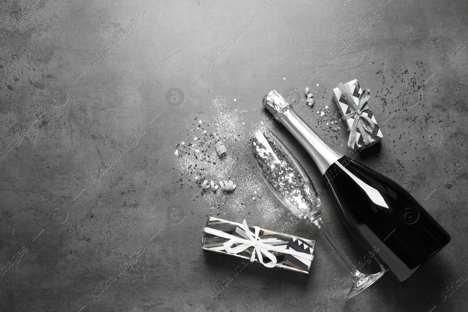 Photo of Flat lay composition with bottle of champagne for celebration on grey stone background. Space for text