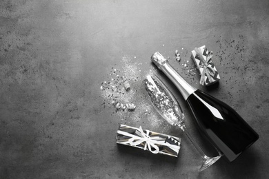 Flat lay composition with bottle of champagne for celebration on grey stone background. Space for text