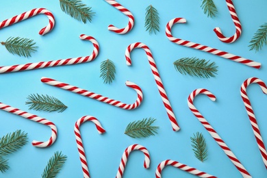 Photo of Flat lay composition with candy canes and fir tree branches on light blue background