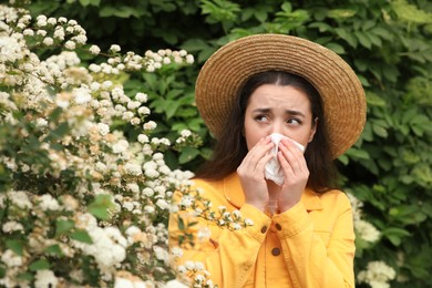 Photo of Woman suffering from seasonal pollen allergy near blossoming tree on spring day