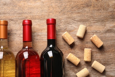 Photo of Flat lay composition with bottles of wine and corks on wooden table