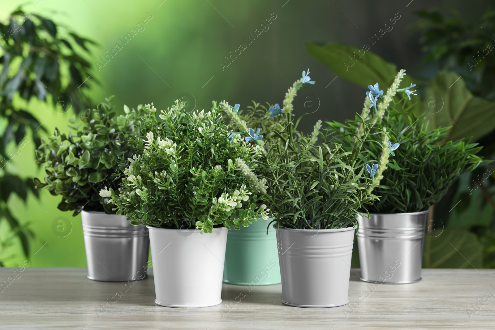 Photo of Different artificial potted herbs on white wooden table outdoors