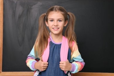 Back to school. Smiling girl with backpack near blackboard