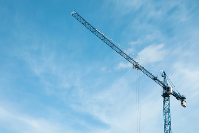 Photo of Tower crane against cloudy sky, low angle view