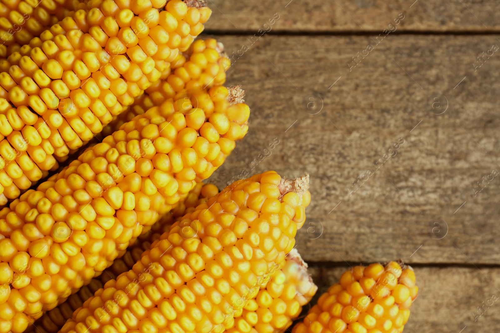 Photo of Delicious ripe corn cobs on wooden table, top view. Space for text