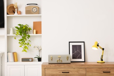 Photo of Spring atmosphere. Chest of drawers and shelves with stylish accessories in room, space for text