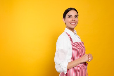 Young woman in red striped apron on yellow background, space for text