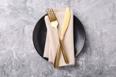 Photo of Elegant setting with golden cutlery on grey textured table, top view