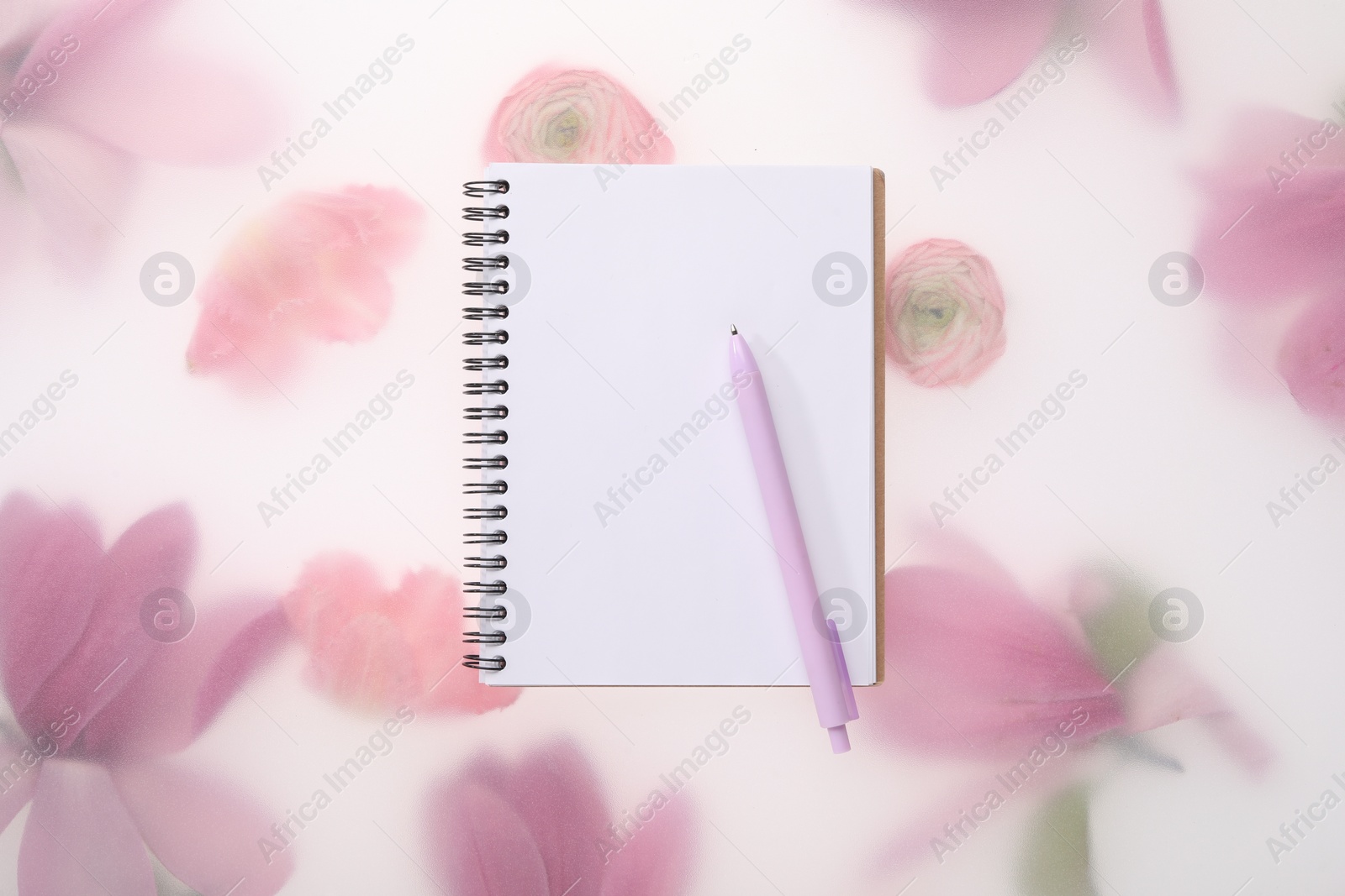 Photo of Guest list. Notebook and pen on spring floral background, top view