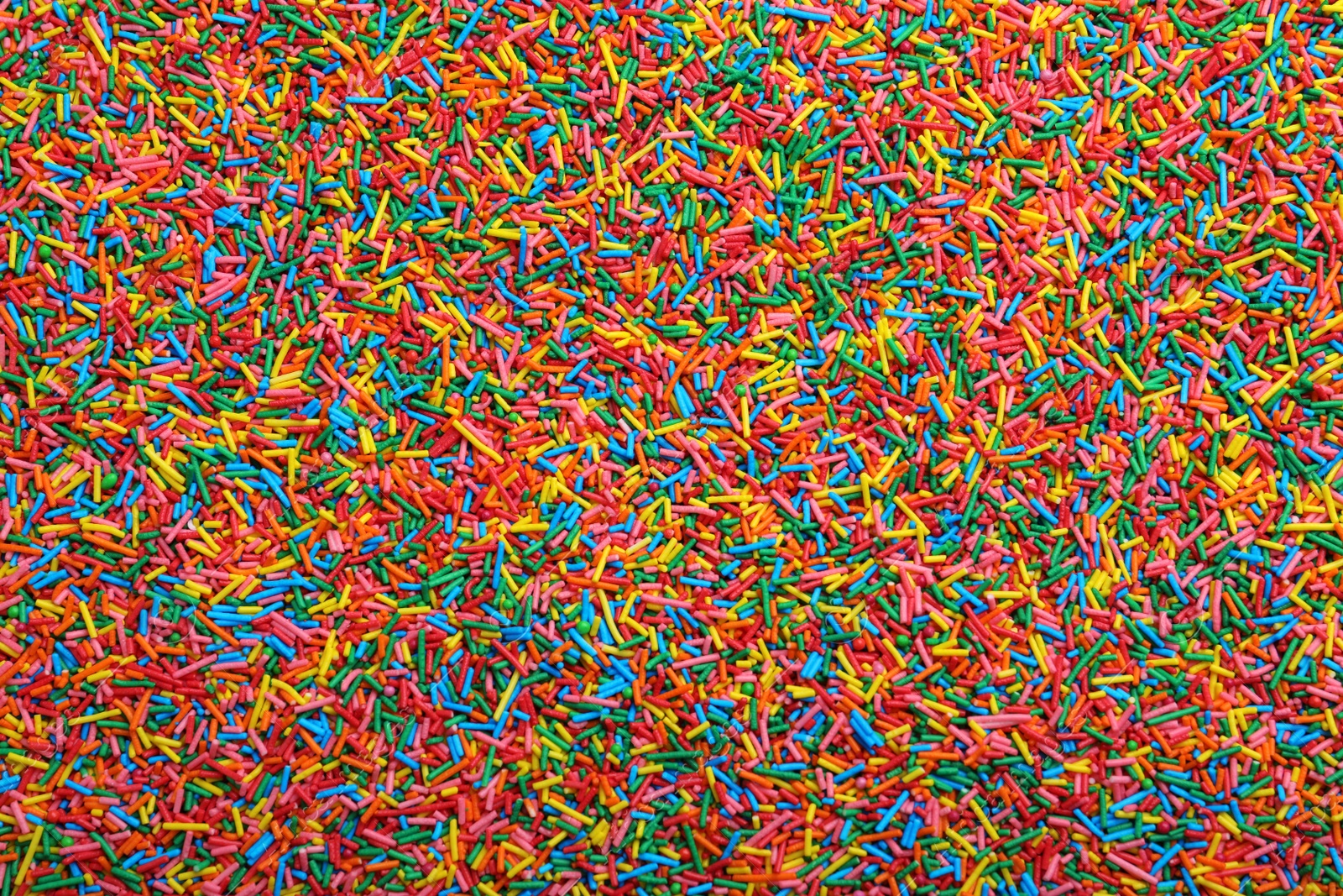 Photo of Bright colorful sprinkles as background, top view. Confectionery decor