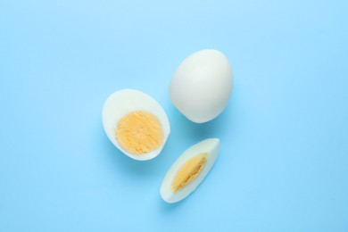 Photo of Fresh hard boiled eggs on light blue background, flat lay