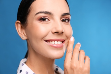 Photo of Young woman with beautiful smile on blue background. Cosmetic dentistry